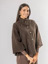 Chaqueta tipo capa de lana bouclé en color marrón, con cuello mao y cierre frontal de botones grandes. Presenta mangas tres cuartos con puños ajustados de tejido acanalado.