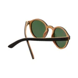 Lentes de sol Indie Hill con montura redonda de madera color marrón oscuro y lentes verdes. Patillas de madera clara.