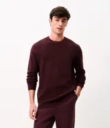 Suéter de punto para hombre color bordó, con textura acanalada horizontal, cuello redondo y mangas largas con puños ajustados.