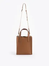 Cartera tipo tote pequeña de cuero color tostado, con doble asa superior y herrajes metálicos plateados en forma de llama en la base de las manijas. Presenta el logo de la marca estampado en la parte inferior frontal.