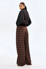 Pantalón sastrero de corte holgado y pierna ancha, con diseño a cuadros en tonos marrones. Presenta pinzas frontales, cintura estándar con cierre oculto, bolsillos laterales al bies y bolsillos traseros insertados.
