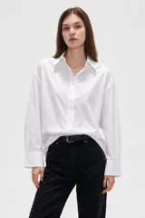 Camisa blanca de algodón, de corte holgado, manga larga con puños anchos y cuello camisero. Cuenta con cierre frontal parcial de botones.