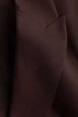 Blazer de botonadura sencilla en mezcla de lino color marrón. Modelo entallado con hombreras, solapas de pico, bolsillos delanteros ribeteados, un botón de cierre y forro interior.