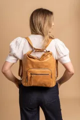 Cartera mochila color tostado, de cuero sintético, con compartimento principal amplio y bolsillos frontales con cierre. Tiene correas ajustables y asa superior para llevar al hombro o como mochila.