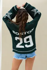 Sweater de punto color verde oscuro, con diseño oversize, mangas largas con estrellas blancas estampadas y la inscripción "BOSTON 29" en la espalda.