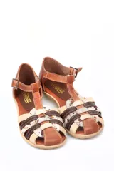 Sandalia tipo arañita Vanzetti con diseño de tiras cruzadas en cuero liso marrón, cuero crema y cuero con textura animal print moteada. Cuenta con cierre de hebilla lateral y suela plana flexible.
