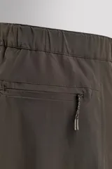 Pantalón largo color verde oscuro, de corte slim fit y tiro medio. Confeccionado en tejido técnico elástico, con cintura ajustable mediante cinturón con hebilla plástica. Presenta bolsillos laterales con cierre de cremallera oculta y bolsillo trasero con cierre de cremallera oculta.