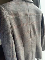 Blazer femenino forrado de corte tradicional, levemente entallado en la cintura, con mini hombreras. Presenta un diseño de cuadros, botón metálico con escudo y costuras en tono contraste.