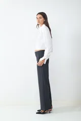 Pantalón de tiro medio color gris oscuro, con pliegues frontales, piernas amplias, bolsillos laterales y cierre frontal con cremallera y botón.