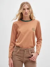 Remera de algodón color ladrillo con rayas horizontales blancas, cuello redondo con ribete verde oscuro, mangas largas y logo bordado en el pecho.