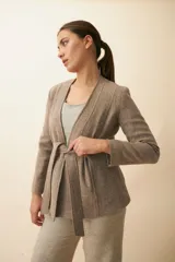 Chaqueta corta color beige, entallada, con escote en V, manga larga y bolsillos escondidos. Cierre frontal con lazo fijo. Confeccionada en lana fina sin teñir. Diseño exclusivo de Don Baez.