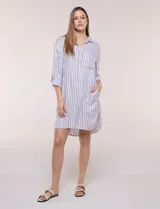 Vestido camisero corto con estampado a rayas verticales en color marrón y blanco, de cuello camisero con escote en V y botones frontales parciales. Cuenta con bolsillos laterales y en el pecho, mangas largas con presillas para ajustar y ruedo curvo asimétrico.