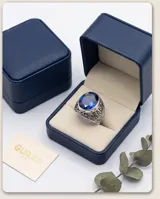 Anillo de plata 925 con diseño calado y piedra facetada azul en forma ovalada.