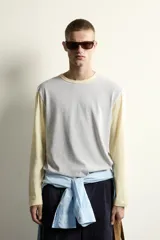 Camiseta de corte relajado con diseño color block, cuerpo en gris melange y mangas largas y cuello redondo en amarillo pastel.