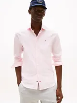 Camisa de popelina rosa claro con tecnología flex, corte slim, cuello abotonado, cierre con botones, logo de Tommy Hilfiger bordado en el pecho y detalles distintivos de la marca.
