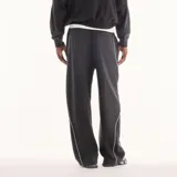 Pantalón de jogging New Balance Trackside negro de corte recto y holgado, con cintura elástica con cordón ajustable, bolsillos laterales y líneas de ribete blancas en contraste. Cuenta con un pequeño logo bordado en la pierna.