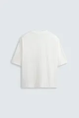 Camiseta gris de corte cuadrado y holgado, con cuello redondo y mangas cortas.