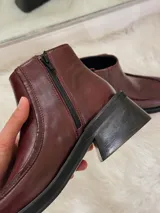 Botas cortas color bordó con punta cuadrada, suela negra y cierre lateral.