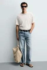 Bolso de hombro confeccionado en tejido trenzado de algodón con diseño de macramé, asa de hombro con detalle de nudo y bolsillo interior plano.