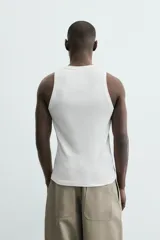 Camiseta tipo tank (sin mangas) de corte relaxed fit, color blanco, con cuello redondo y un pequeño estampado gráfico en el pecho que dice "SANTA BARBARA EST. 1987 CALIFORNIA".