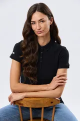 Remera polo de piqué negro, de manga corta, con cuello clásico y cierre frontal de botones.