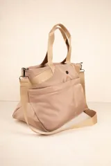 Bolso tipo shopper color beige, con asas fijas superiores y correa desmontable y regulable. Cuenta con dos bolsillos externos y tres bolsillos internos.