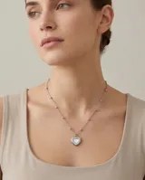 Collar de acero con cadena de eslabones y pequeñas cuentas esféricas, con dije colgante en forma de corazón con incrustación de nácar.