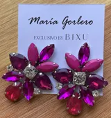 Par de caravanas con forma de flor, con pétalos de diferentes tamaños y colores: fucsia, violeta y rojo. En el centro tienen un cristal facetado y pequeños strass blancos.