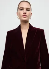 Blazer de terciopelo color bordó, con solapas con muesca, cierre frontal de un botón, bolsillos laterales con solapa y mangas largas con puños abotonados.