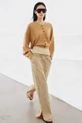 Pantalón de tiro medio con diseño de rayas verticales en tonos beige y marrón. Presenta una cintura elástica ajustable con cordones, bolsillos laterales ocultos y corte de pierna recta con aberturas en el bajo.