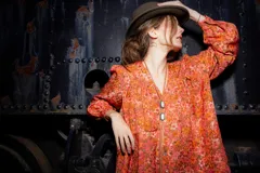 Camisa de seda con estampado floral en tonos naranjas y rosados, de corte amplio y estilo boho. Presenta mangas largas abullonadas, frunces en hombros y espalda, y cierre frontal con botones.