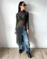 Vestido largo de tela transparente con acabado brillante, cuello alto y manga larga. Presenta un tajo frontal pronunciado y diseño ajustado.