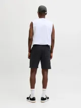 Bermuda deportiva negra de calce relajado, con cintura elástica ajustable mediante cordón, bolsillos laterales y costuras frontales en relieve. Presenta un pequeño estampado de texto en la pierna izquierda.