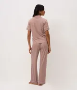 Pijama largo de dos piezas confeccionado en ribana con estampado de cuadros vichy en tonos marrón y blanco. Incluye una blusa de manga corta con cuello solapa, cierre frontal de botones y detalles de vivo contrastante, y un pantalón de pierna recta con cintura elástica.