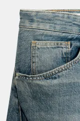 Jeans de tiro medio y corte baggy oversize con diseño de costuras marcadas en las piernas, trabillas para cinturón y cinco bolsillos tradicionales. Cierre frontal con cremallera y botón metálico.