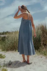 Vestido midi de denim color celeste, con escote recto, breteles finos y corte evasé amplio.