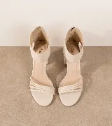 Sandalias de tacón alto en color negro, confeccionadas en 100% cuero vacuno. Presentan un diseño elegante con tiras finas en la parte delantera y una pulsera ancha en el tobillo con cierre de cremallera en la parte trasera. Cuenta con un taco ancho.