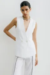 Chaleco sastrero blanco de lino, con cuello en V profundo y cierre cruzado con botones.