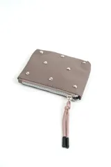 Billetera de cuero sintético color marrón topo, con cierre de cremallera y tirador de cordón rosado con punteras negras. Está decorada con tachas metálicas plateadas en forma de corazón distribuidas en el frente.