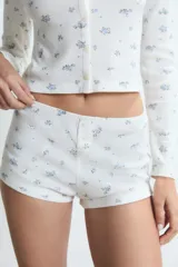 Pijama de dos piezas compuesto por una remera de manga larga con botones frontales y un short de tiro alto, ambos confeccionados en tejido acanalado con estampado floral pequeño.