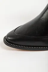 Bota de caña media combinada, con puntera y talón en cuero negro y caña de tejido de punto acanalado elástico. Cuenta con taco cuadrado bajo y tirador trasero.