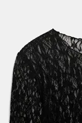 Top de manga larga confeccionado en tejido de encaje con diseño floral, de color blanco y corte recto con cuello redondo.