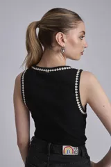 Remera negra sin mangas, tipo musculosa, con escote redondo y ribetes blancos con apliques de perlas en el contorno del cuello y las sisas.
