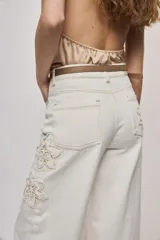 Jean wide leg blanco de tiro medio, con calce amplio y detalle de flores bordadas en los laterales.