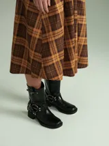 Botas de caña media confeccionadas en cuero texturado color marrón. Presentan un diseño robusto con múltiples hebillas metálicas ajustables, apliques circulares laterales y punta cuadrada. Cuentan con un taco cuadrado de 5 cm de altura.