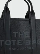 Bolso tote pequeño de cuero texturizado color gris con doble asa corta superior y correa larga extraíble y ajustable para llevar al hombro. Estampado frontal con el texto "The Tote Bag" y el nombre de la marca.