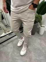 Jean de corte skinny en color beige, confeccionado en tejido con elasticidad. Presenta diseño clásico de cinco bolsillos y cierre frontal con botón y cremallera.