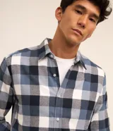 Camisa de franela para hombre, modelo comfort, con estampado de cuadros en tonos azules, blancos y negros, cuello camisero, manga larga y cierre frontal de botones.