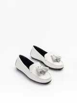 Mocasín plano Bert de punta redondeada, confeccionado en cuero vacuno color blanco con costuras artesanales y detalle de borla de flecos en el empeine, sobre suela de goma.