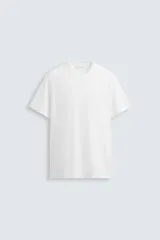 Camiseta de algodón de peso medio, color blanco, con cuello redondo y manga corta. Presenta un ligero efecto lavado.